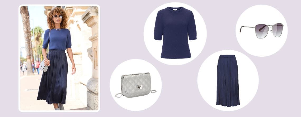 Frau in blauem Oberteil und Rock trägt silberne Tasche. Grau-schwarze Sonnenbrille, blaues Oberteil, Rock und silberne Tasche rechts.