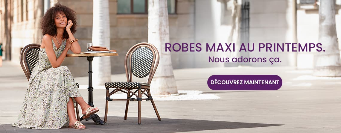 Robes maxi au printemps – Femme assise en robe longue fleurie à une terrasse, bouton « Découvrez maintenant »