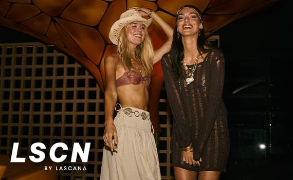 LSCN by LASCANA – zwei Frauen in Strandmode posieren abends vor beleuchteter Kulisse