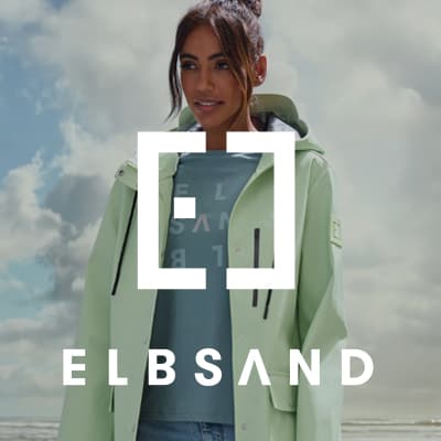 ELBSAND Logo vor Frau im hellen Mantel am Strand, Meer und bewölkter Himmel im Hintergrund