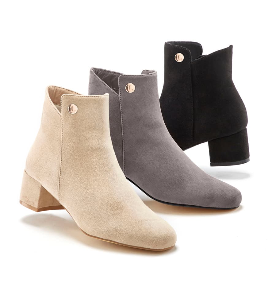 Trois bottines à talon moyen avec bouton décoratif, en beige, gris et noir, alignées de profil