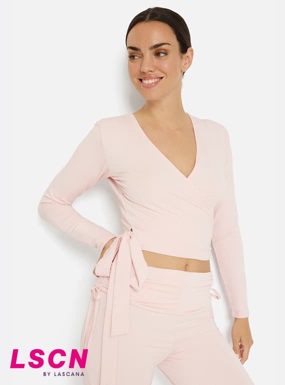 Femme portant un ensemble rose LSCN by Lascana, top cache-cœur à liens et pantalon assorti